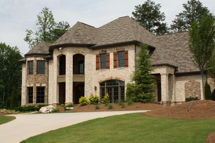 Large brick and stone mansion with arched windows and a circular driveway