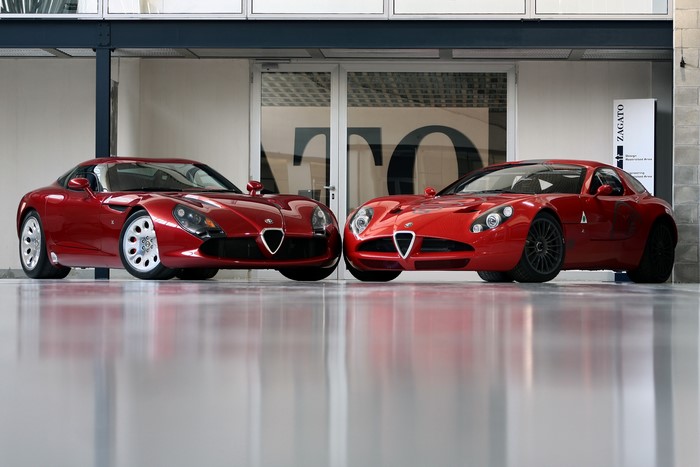 Two red Alfa Romeo cars parked indoors