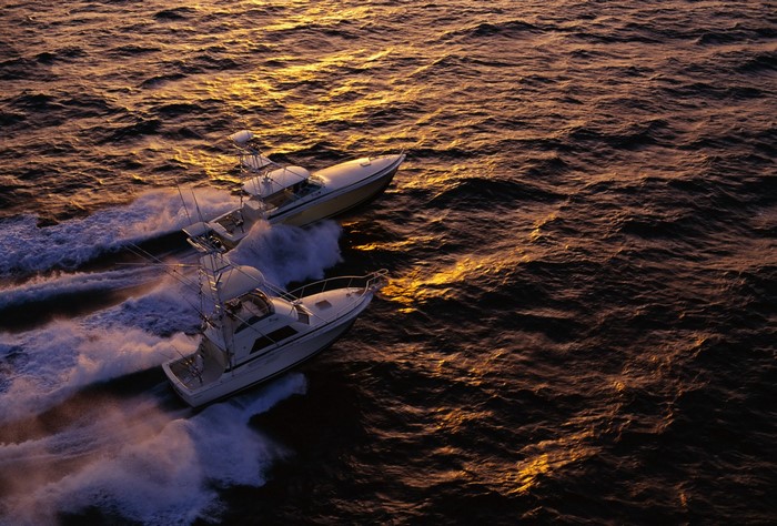 Two motorboats racing on the ocean at sunset