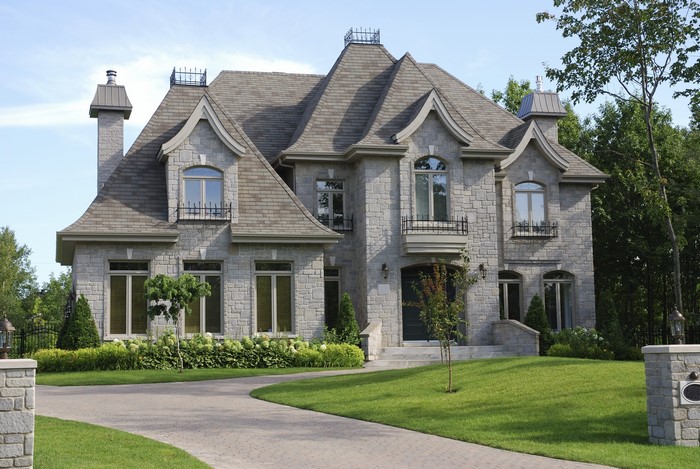 Stone mansion with manicured lawn and driveway
