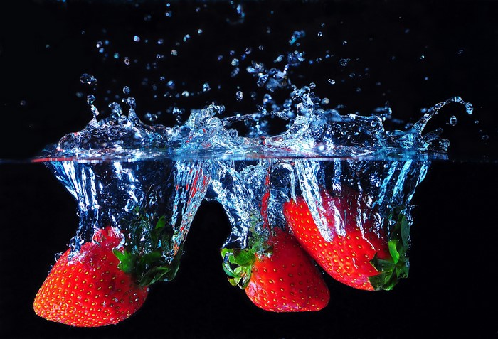 Strawberries splashing into water