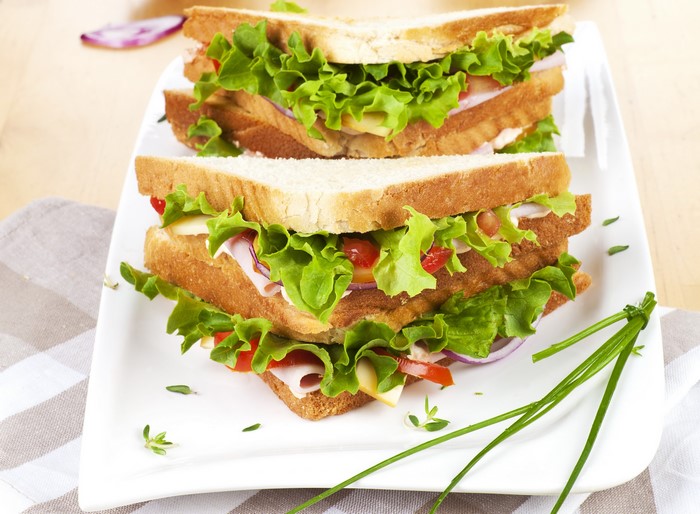 Two stacked sandwiches with lettuce, tomato, and ham