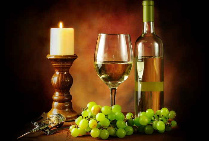 Still-life with white wine, grapes, candle, and corkscrew