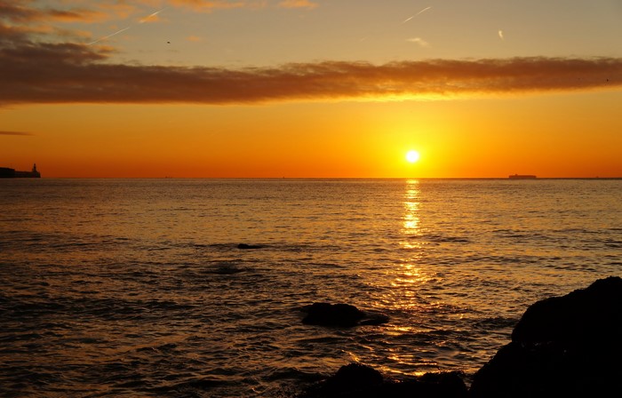 Sunset over the sea with ships on the horizon