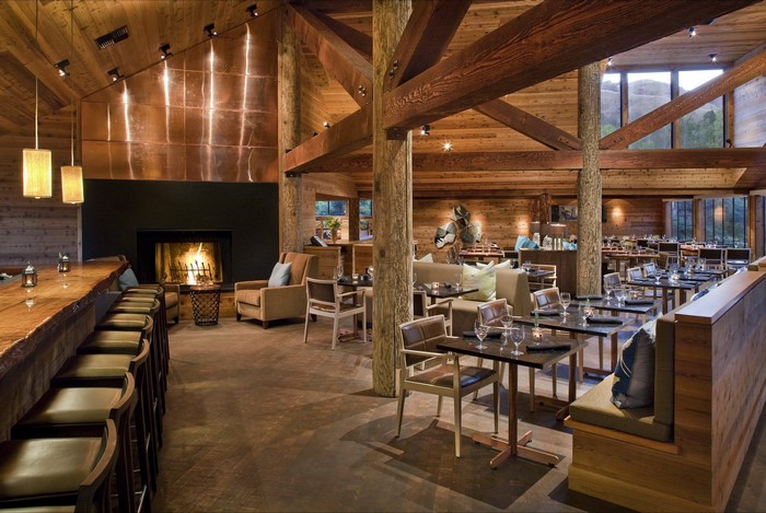 Interior of a rustic wooden restaurant with a fireplace and bar