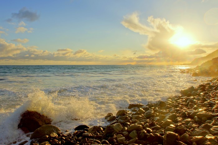 Ocean waves crashing on a rocky shore at sunset