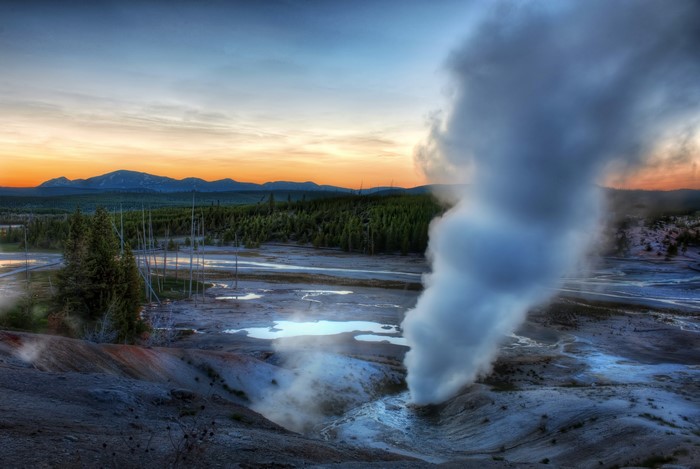 Steam erupting from geyser in Yellowstone National Park at sunset