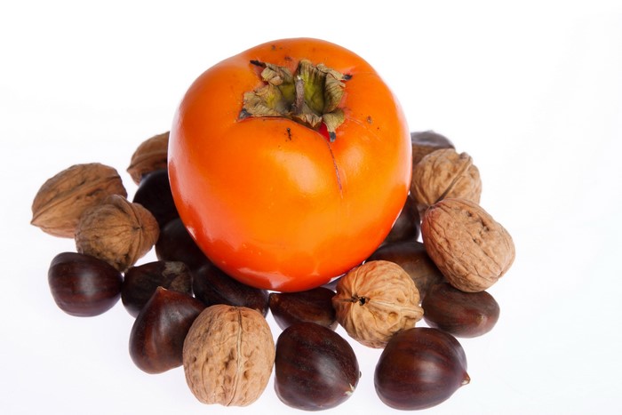 Persimmon and walnuts on a white background