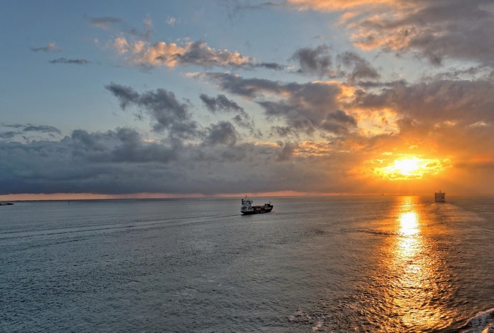 Cargo ships sailing on the sea at sunset near Rotterdam