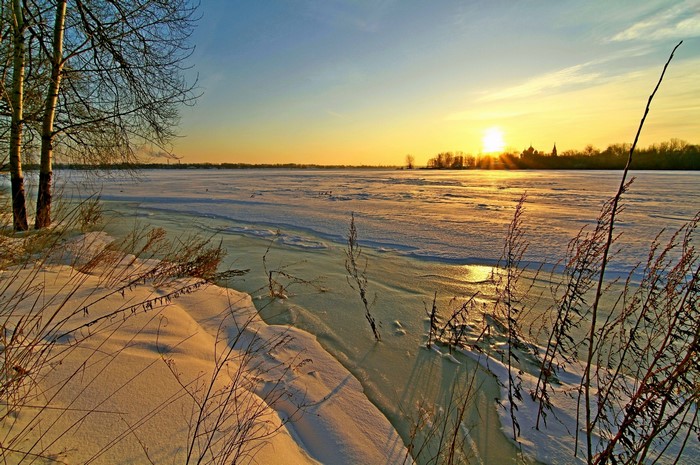 Winter sunset over a frozen river with snow and ice