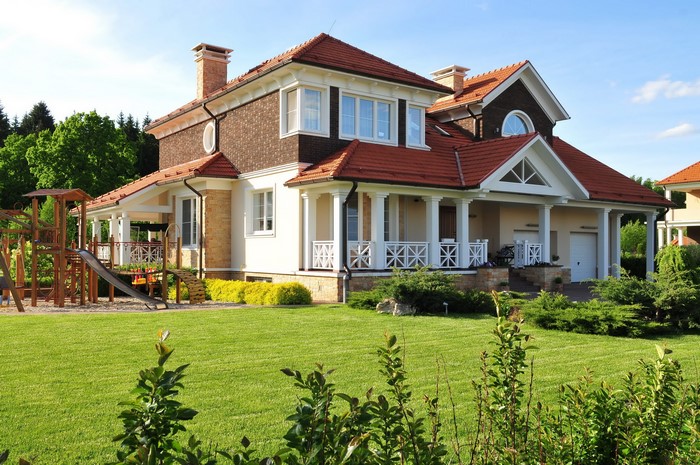 A large modern house with a playground and a green lawn