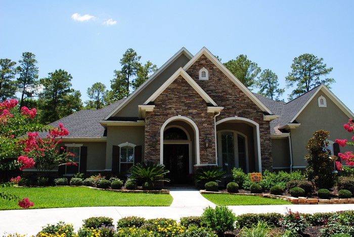 Luxury house with stone facade and manicured landscaping
