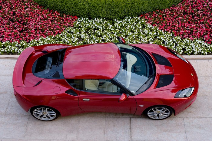 Red 2010 Lotus Evora parked near flowers