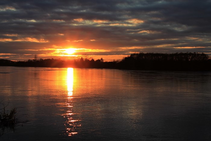 Sunset over a river with dark clouds