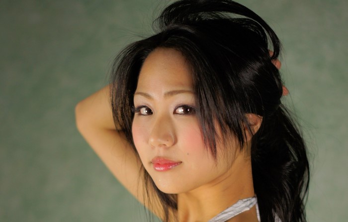 Asian woman with dark hair touching her head