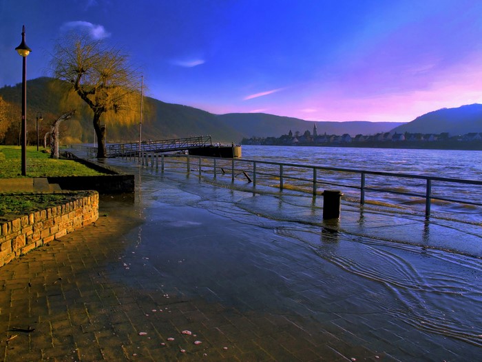 Flooded river promenade with a town in the distance