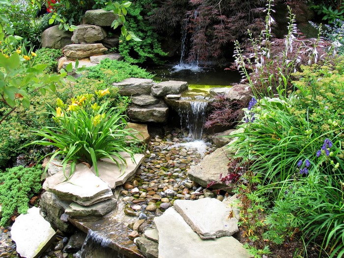 Stone waterfall and stream in a garden with flowers