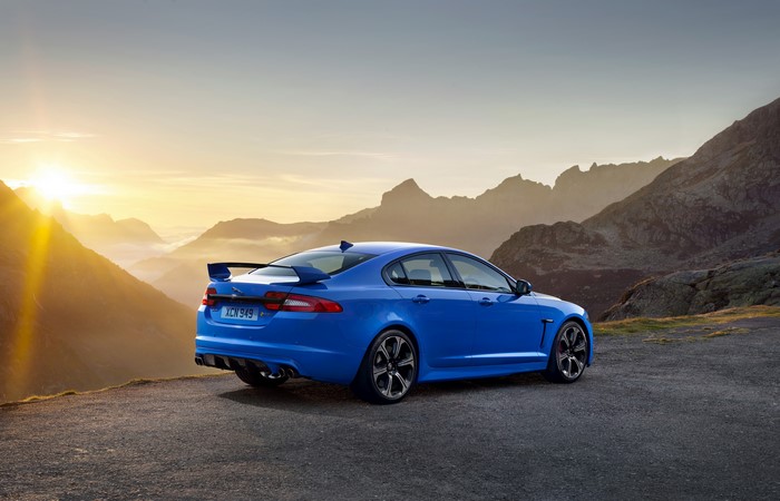 Blue Jaguar XFR-S parked on mountain road at sunset