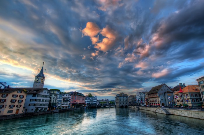 River with buildings and clock tower under cloudy sky