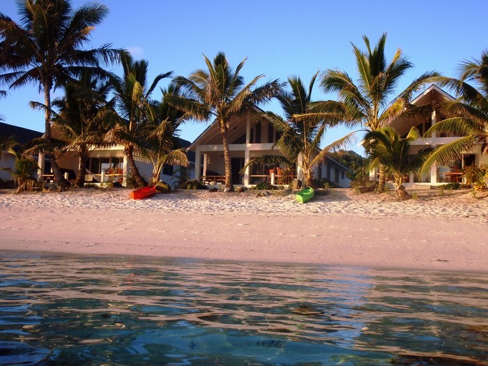 Beach bungalows with palm trees and kayaks in the Cook Islands
