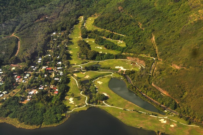 Aerial view of a golf course and village in a tropical landscape