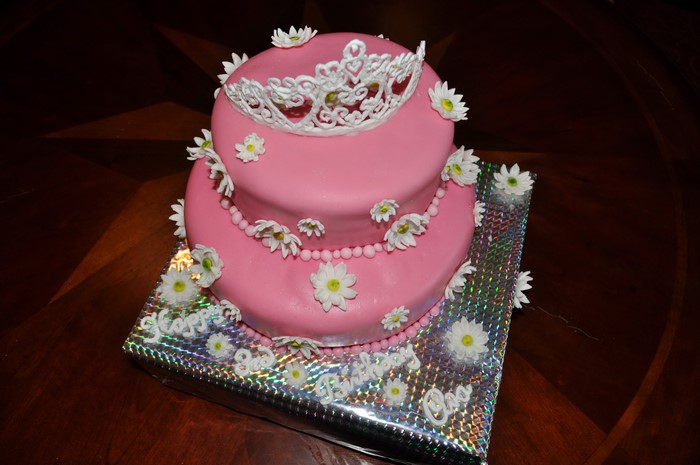 Two-tiered pink cake with tiara and daisies
