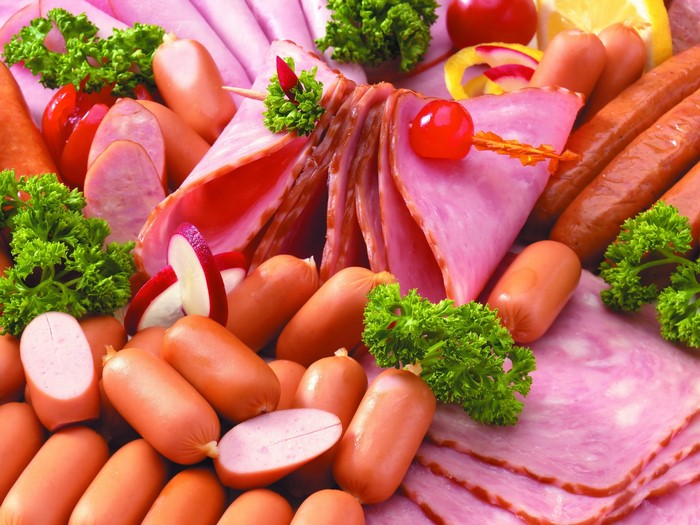 Assortment of sausages and sliced ham with parsley and cherry tomatoes