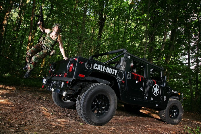 Woman in camouflage jumping from a Call of Duty Hummer