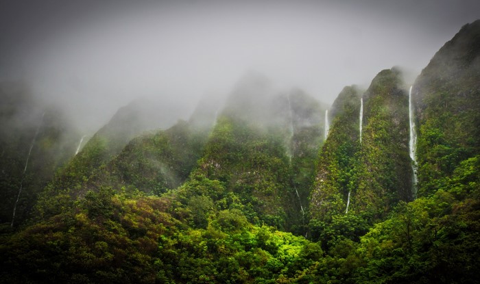 Waterfalls cascading down misty green mountains in Hawaii