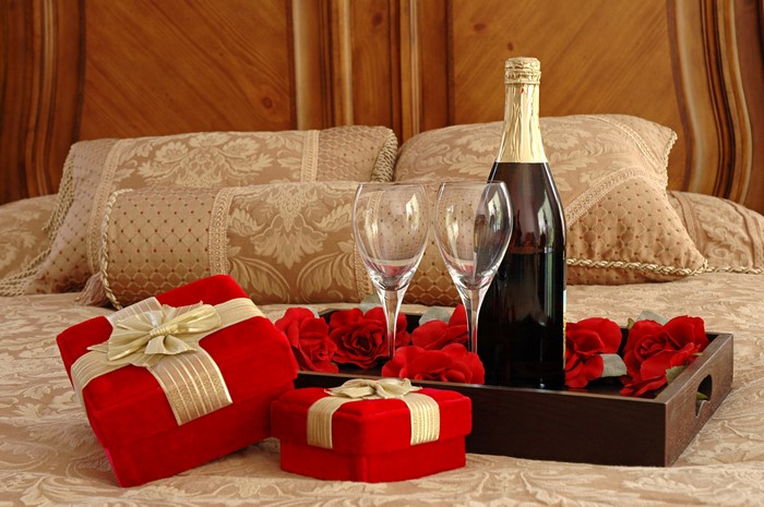 Champagne, Gifts, and Roses on a Bed
