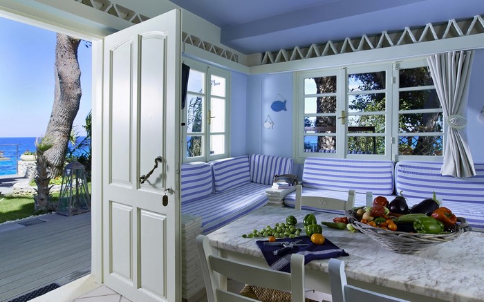 Interior with vegetables on table and opened door to the sea