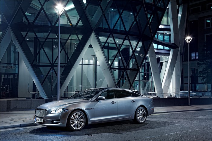 Silver Jaguar XJ LWB parked in front of a modern building at night