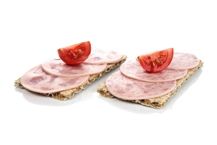 Two open-faced sandwiches with sausage and tomato