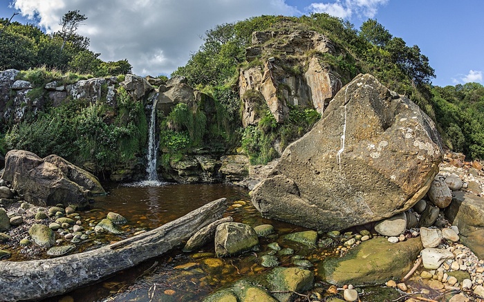 Waterfall cascading into a rocky pool with large boulders