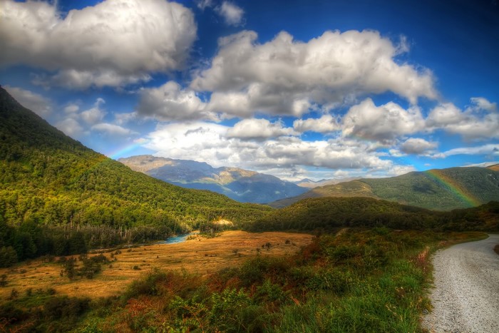 Mountain valley with rainbow and clouds