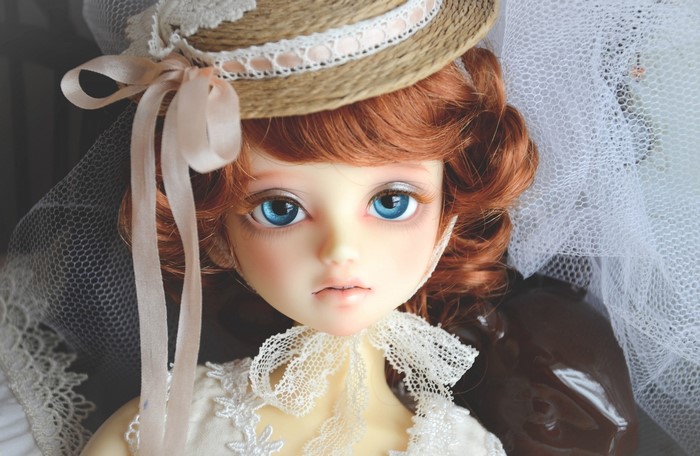 Doll with red hair wearing a straw hat and lace dress