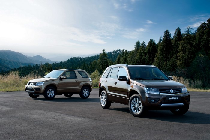 Two Suzuki Grand Vitara SUVs on a mountain road