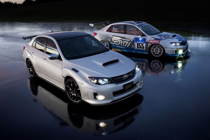 Two Subaru WRX STi cars on wet asphalt
