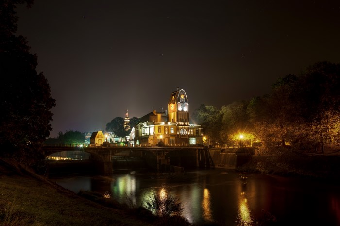 Building with clock tower over river at night