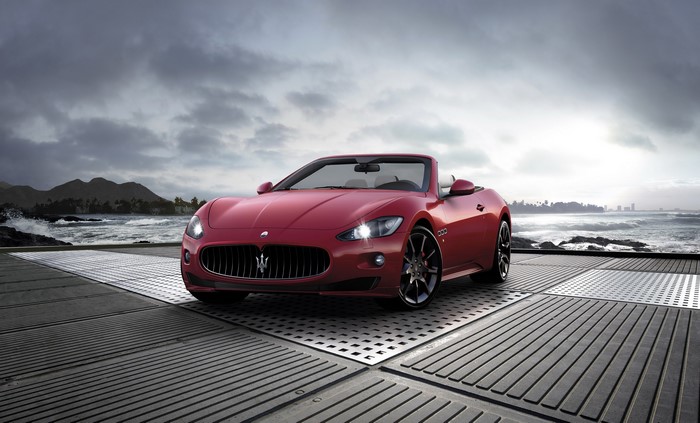 Red Maserati Gran Cabrio Sport convertible on a platform by the ocean