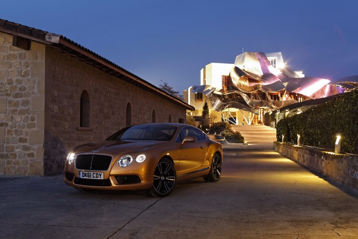 Bentley Continental GT parked outside a modern building at dusk