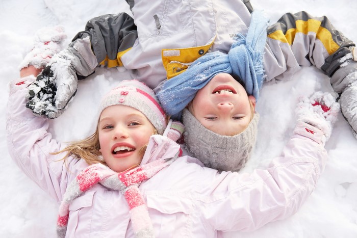 Two young girls lying in the snow