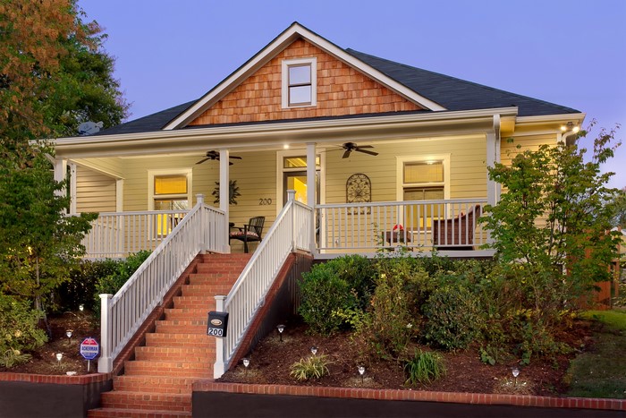 Yellow house with a porch and stairs at dusk