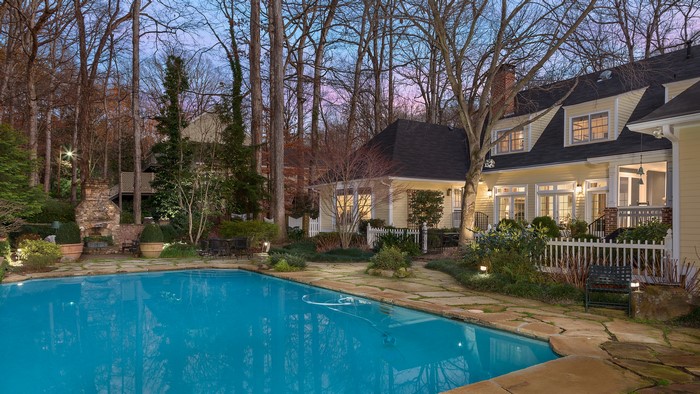 Yellow house with a swimming pool and trees