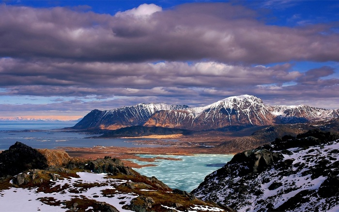 Snow-capped mountains and a frozen lake under a cloudy sky