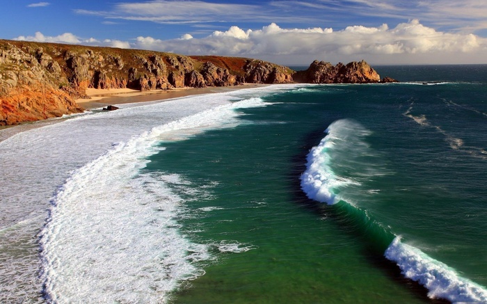 Coastal cliffs and ocean waves under a cloudy sky