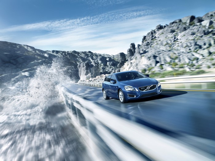 Blue Volvo V60 driving on a coastal road with waves