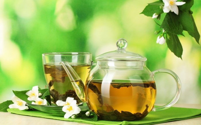 Jasmine tea in a glass teapot and cup with flowers
