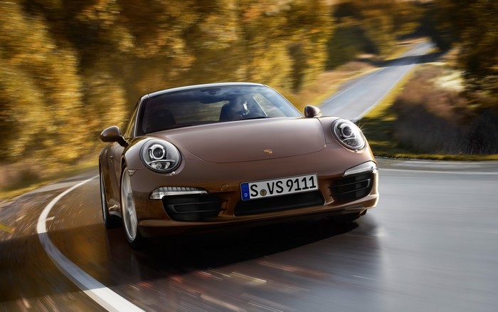 Brown Porsche 911 driving on a winding road
