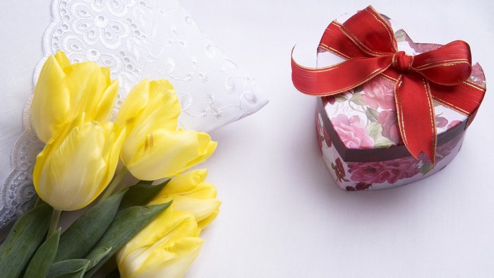 Yellow tulips and heart-shaped gift box with red ribbon
